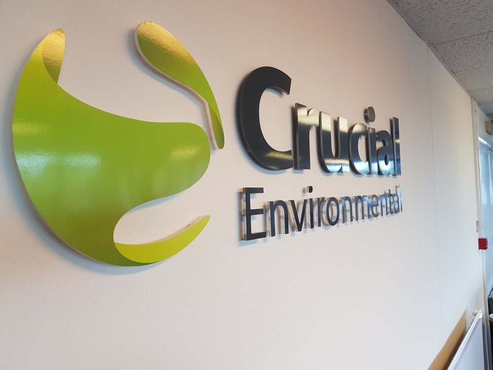 Flat cut Crucial Environmental logo and lettering installed on an interior wall
